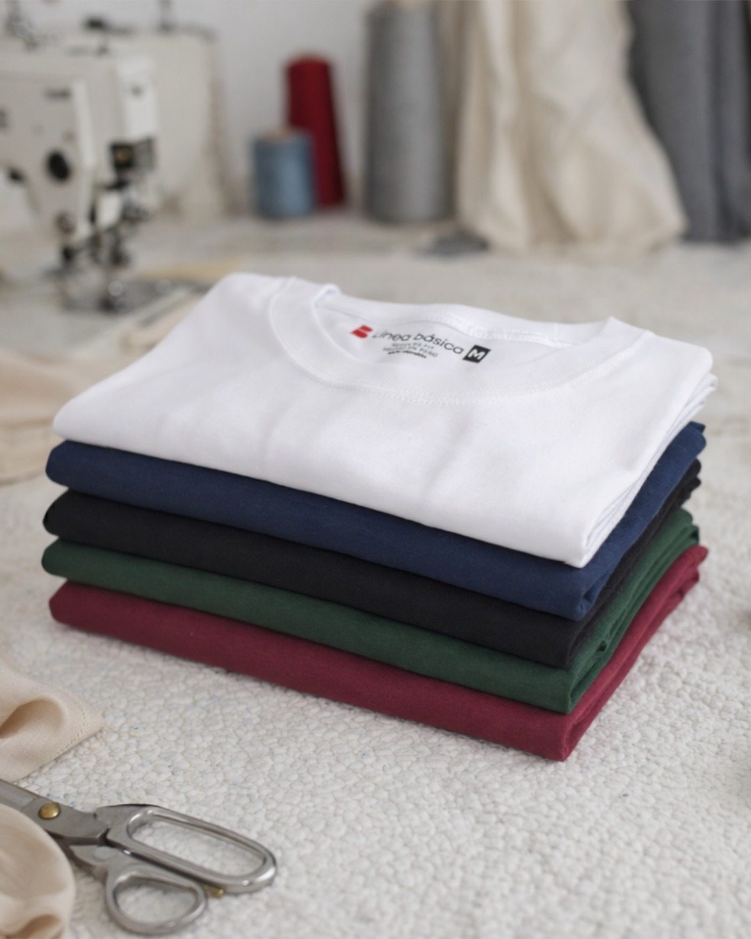 Cinco polos Línea básica doblados y apilados: blanco, azul marino, negro, verde botella y guinda